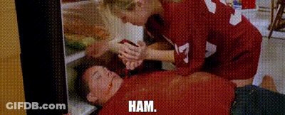 A Woman Is Putting Ham In A Man 'S Mouth . GIF