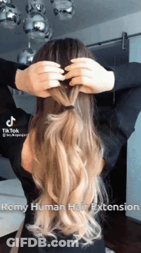 A Woman Is Putting Her Hair In A Braid . GIF