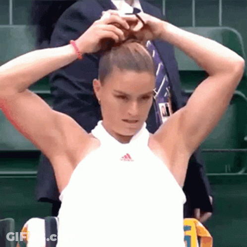 A Woman Is Putting Her Hair In A Bun While A Man In A Suit Is Standing Behind Her . GIF
