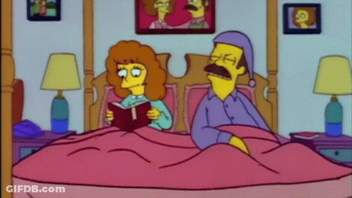 A Woman Is Reading A Book To A Man Who Is Sleeping In A Bed . GIF