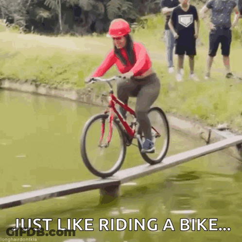 A Woman Is Riding A Bike On A Wooden Bridge Over A Body Of Water . GIF