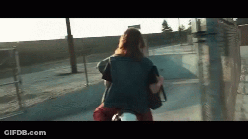A Woman Is Riding A Motorcycle Down A Street With A Backpack . GIF