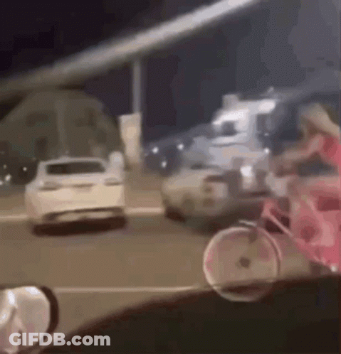 A Woman Is Riding A Pink Bicycle Down A Street Next To A Car . GIF