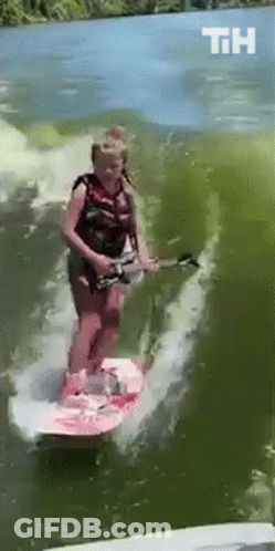 A Woman Is Riding A Surfboard In The Water And The Letters Th Are Visible GIF