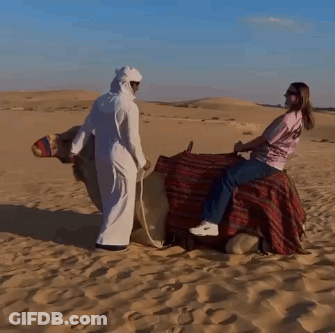 A Woman Is Riding On The Back Of A Camel GIF