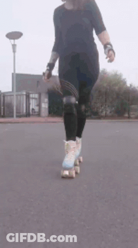 A Woman Is Rollerblading Down A Street With A Street Light In The Background . GIF
