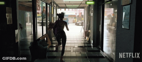 A Woman Is Running Down A Hallway With A Netflix Logo In The Corner GIF