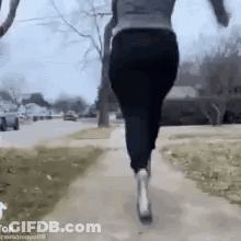 A Woman Is Running Down A Sidewalk With A Dog In Her Arms . GIF
