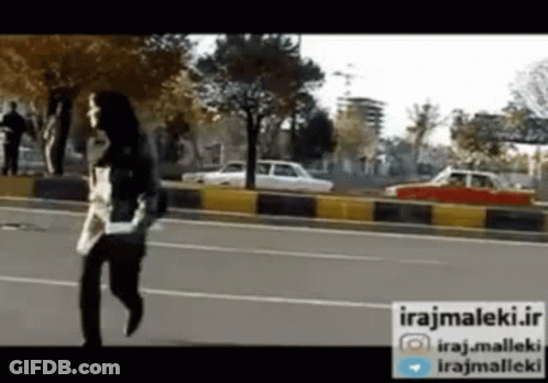 A Woman Is Running Down A Street With A Sign That Says Irajmaleki.ir GIF