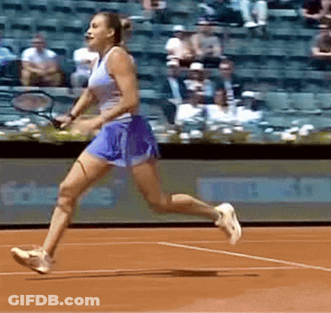 A Woman Is Running On A Tennis Court Holding A Racket GIF