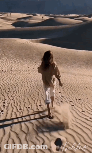 A Woman Is Running Through A Desert With A Ladder In The Sand GIF