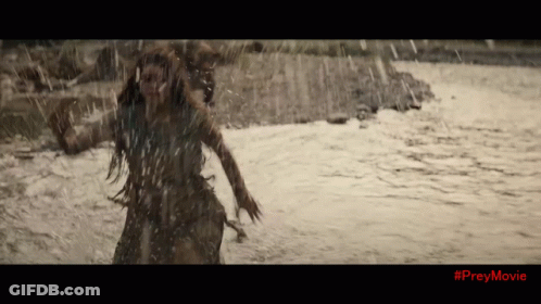 A Woman Is Running Through A River With #Preymovie On The Bottom Of The Screen GIF