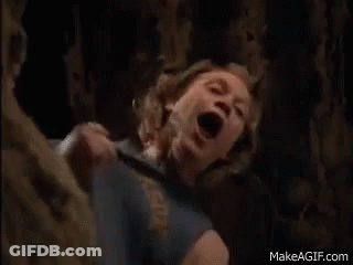 A Woman Is Screaming In A Cave With Her Mouth Open While A Man Is Holding Her . GIF