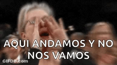A Woman Is Screaming In A Crowd Of People While Covering Her Face . GIF