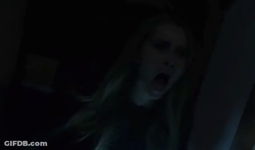 A Woman Is Screaming In A Dark Room With Her Mouth Wide Open . GIF