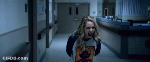 A Woman Is Screaming In A Hallway And Wearing A Shirt That Says Guns N Roses GIF