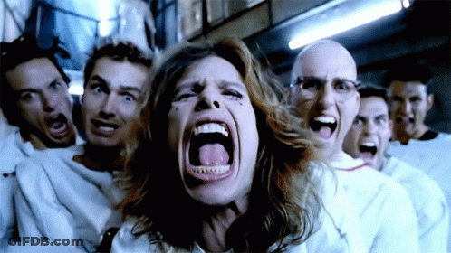 A Woman Is Screaming In Front Of A Group Of Men In White Shirts GIF