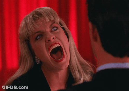 A Woman Is Screaming In Front Of A Man With A Red Curtain Behind Her GIF
