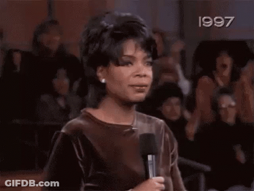 A Woman Is Screaming With Her Hands In The Air In A Crowd Of People . GIF