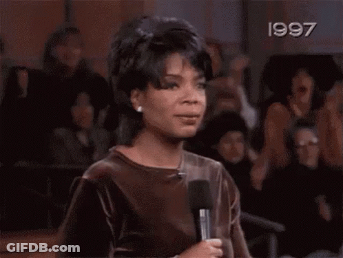 A Woman Is Screaming With Her Hands In The Air In A Crowd . GIF
