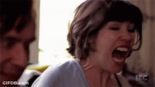 A Woman Is Screaming With Her Mouth Open And A Man Is Standing Behind Her . GIF