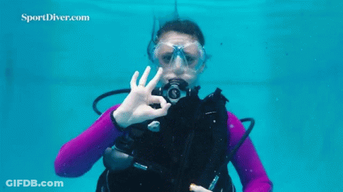 A Woman Is Scuba Diving In A Pool And Making An Ok Sign With Her Hand . GIF