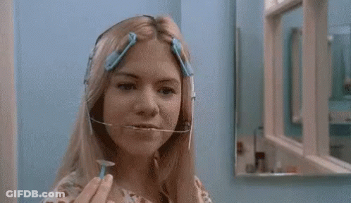A Woman Is Shaving Her Face With A Razor In Front Of A Mirror In A Bathroom . GIF