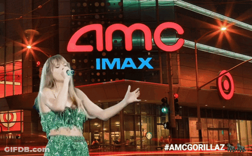 A Woman Is Singing In Front Of An Amc Imax Sign GIF