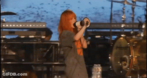 A Woman Is Singing Into A Megaphone On A Stage GIF
