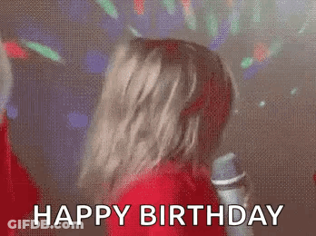 A Woman Is Singing Into A Microphone At A Birthday Party And Says `` Happy Birthday '' . GIF