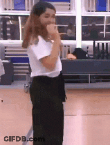 A Woman Is Singing Into A Microphone In A Room . GIF