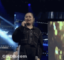 A Woman Is Singing Into A Microphone On A Stage While Crying . GIF