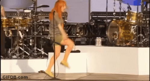 A Woman Is Singing Into A Microphone On Stage GIF