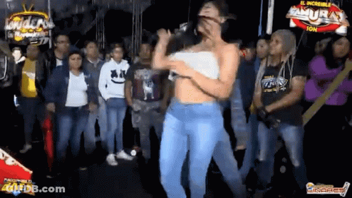 A Woman Is Singing Into A Microphone While Dancing In Front Of A Crowd Of People . GIF