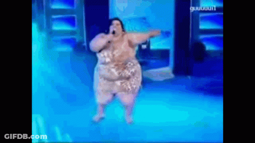 A Woman Is Singing Into A Microphone While Dancing On A Stage . GIF