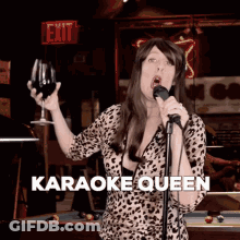 A Woman Is Singing Into A Microphone While Holding A Glass Of Wine And The Words Karaoke Queen Are On The Bottom GIF
