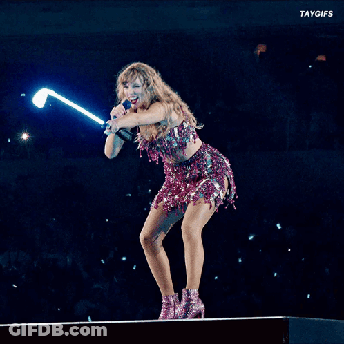 A Woman Is Singing Into A Microphone While Holding A Light Stick GIF