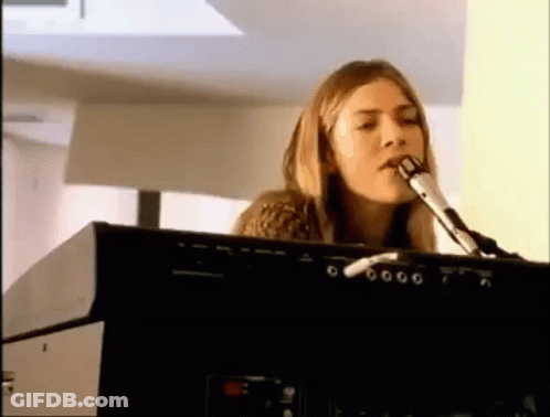 A Woman Is Singing Into A Microphone While Playing An Electronic Keyboard . GIF