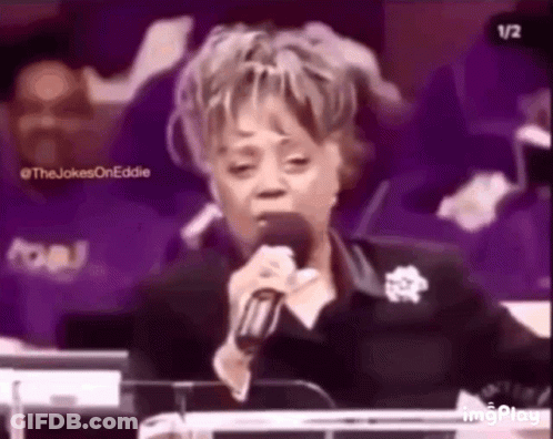 A Woman Is Singing Into A Microphone While Sitting At A Podium In A Church . GIF
