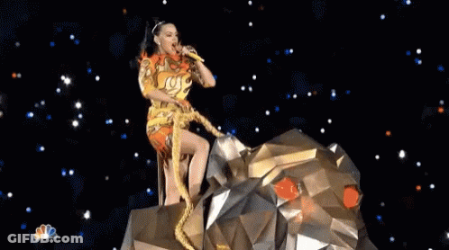 A Woman Is Singing Into A Microphone While Sitting On Top Of A Statue Of A Lion . GIF