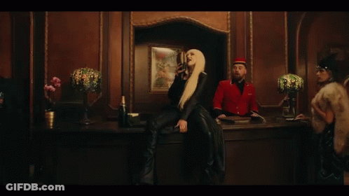 A Woman Is Singing Into A Microphone While Wearing A Black Jacket . GIF