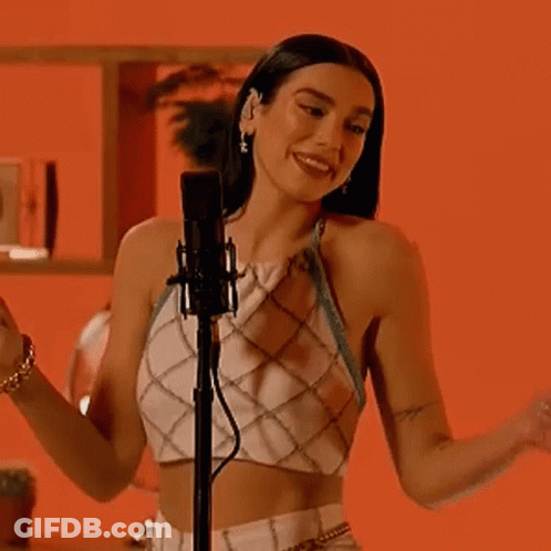 A Woman Is Singing Into A Microphone While Wearing A Crop Top . GIF