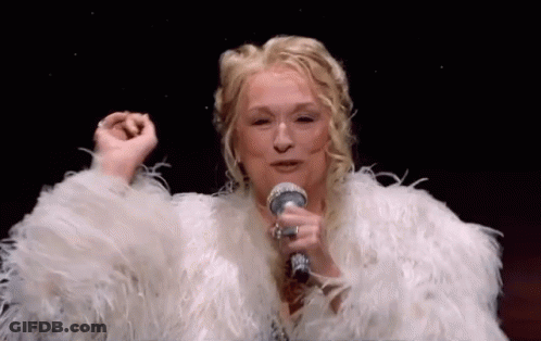 A Woman Is Singing Into A Microphone While Wearing A White Fur Coat . GIF