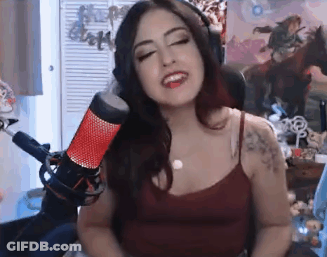 A Woman Is Singing Into A Microphone While Wearing Headphones And A Red Tank Top . GIF