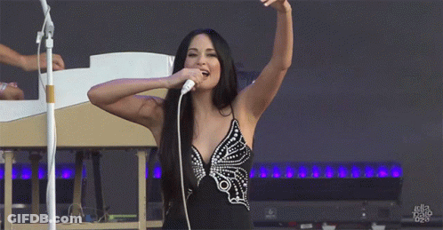 A Woman Is Singing Into A Microphone With Her Arms In The Air And The Word Ella On The Bottom Left GIF