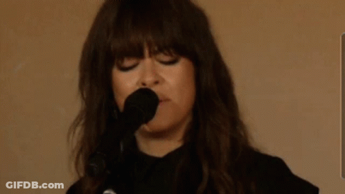A Woman Is Singing Into A Microphone With The Words Sie7evec Written In The Background GIF