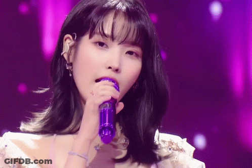 A Woman Is Singing Into A Purple Microphone . GIF