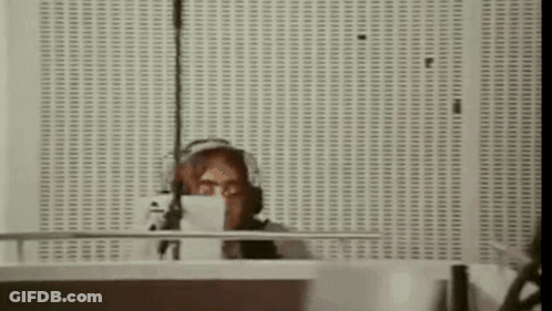A Woman Is Sitting At A Desk In Front Of A Microphone . GIF