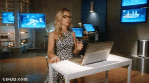 A Woman Is Sitting At A Desk Using A Laptop Computer GIF