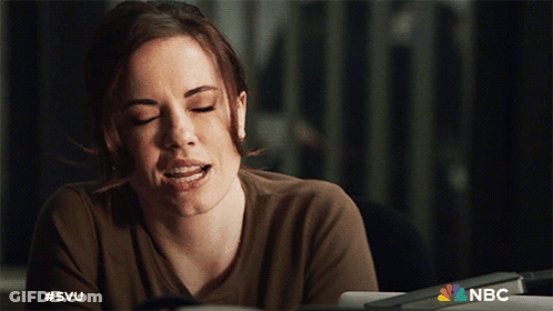 A Woman Is Sitting At A Desk With Her Eyes Closed And The Nbc Logo Behind Her GIF
